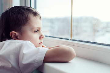 Image showing sad little boy sitting near the window