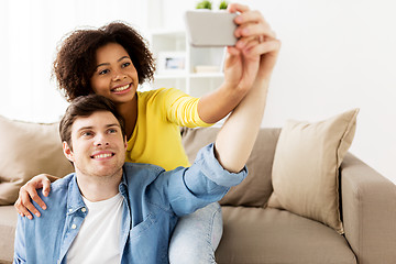 Image showing happy couple with smartphone taking selfie at home