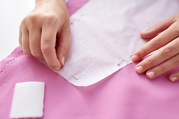 Image showing woman with pins stitching paper pattern to fabric