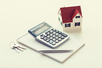 Image showing close up of home model, calculator and notebook