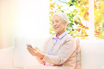 Image showing senior woman with smartphone texting at home