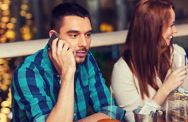 Image showing man with smartphone and friends at restaurant