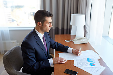 Image showing businessman with papers working at hotel room