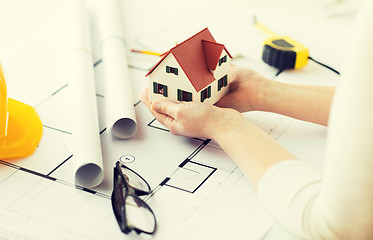 Image showing close up of hands with house model above blueprint