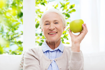 Image showing happy senior woman with green apple at home