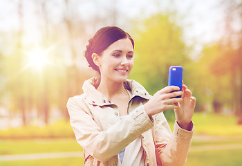 Image showing smiling woman taking picture with smartphone