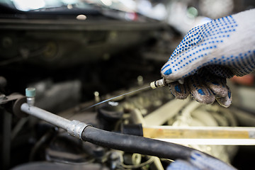 Image showing mechanic with dipstick checking motor oil level