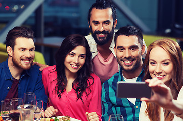 Image showing friends taking selfie by smartphone at restaurant