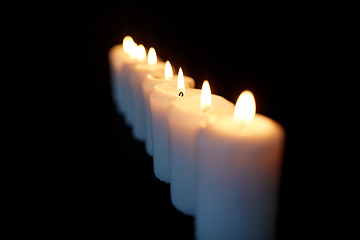 Image showing candles burning in darkness over black background