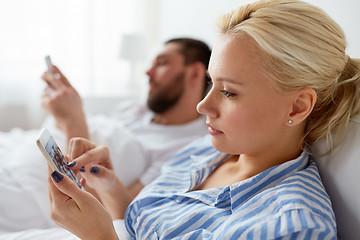 Image showing couple with smartphones in bed at home