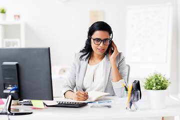 Image showing businesswoman with headset and notebook at office