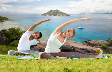 Image showing happy couple making yoga exercises outdoors