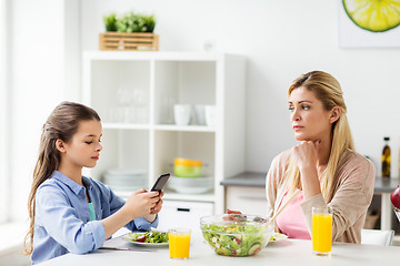 Image showing sad woman looking at her daughter with smartphone