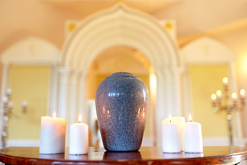 Image showing cremation urn and candles burning in church