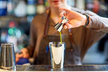 Image showing bartender with cocktail shaker and jigger at bar