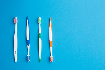 Image showing Multi-colored toothbrushes on blue background