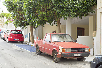 Image showing Old rusty red car standing in the street