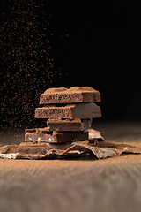 Image showing Broken chocolate on wooden table