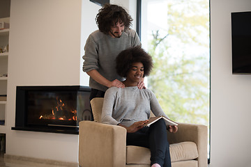 Image showing multiethnic couple hugging in front of fireplace