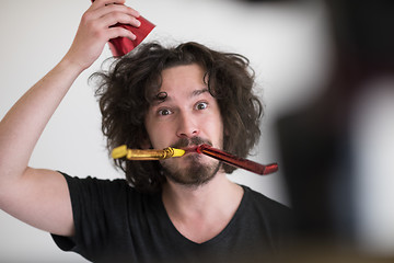 Image showing Portrait of a man in party hat blowing in whistle