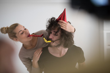 Image showing couple in party hats blowing in whistle