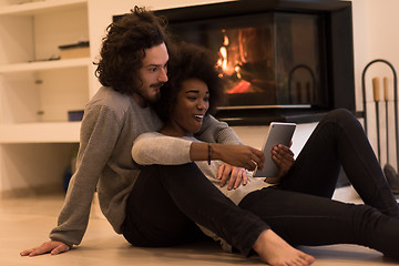 Image showing multiethnic couple using tablet computer on the floor