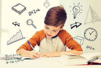 Image showing smiling student boy writing to notebook at home