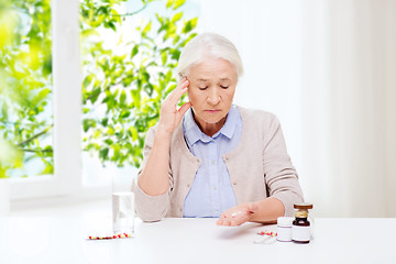 Image showing senior woman with water and medicine at home