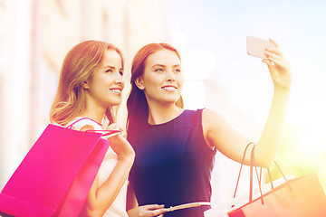 Image showing happy women with shopping bags and smartphone