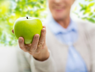 Image showing close up of senior woman hand holding green apple