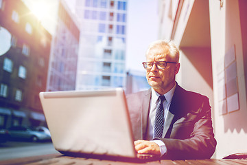 Image showing senior businessman with laptop at city street cafe