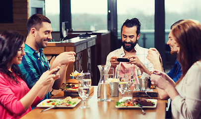 Image showing happy friends taking picture of food at restaurant