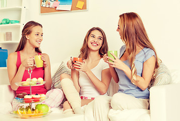 Image showing happy young women drinking tea with sweets at home