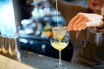 Image showing bartender pouring cocktail into glass at bar