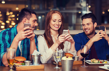 Image showing happy friends with smartphones at restaurant