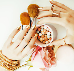 Image showing woman hands with golden manicure and many rings holding brushes,