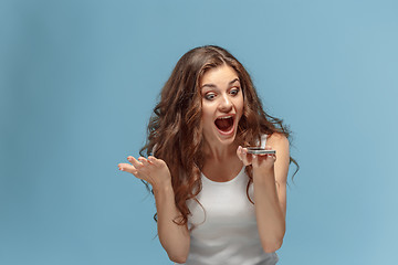 Image showing Shocked woman looking at mobile phone on green background