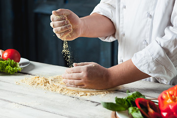 Image showing Closeup hand of chef baker in white uniform making pizza at kitchen