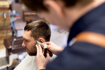 Image showing man and barber hands with trimmer cutting hair