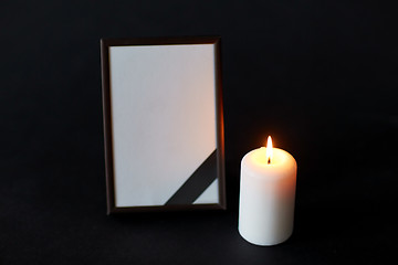 Image showing black ribbon on photo frame and candle at funeral