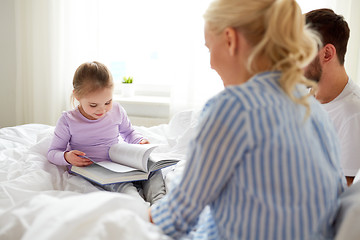 Image showing happy family reading book in bed at home