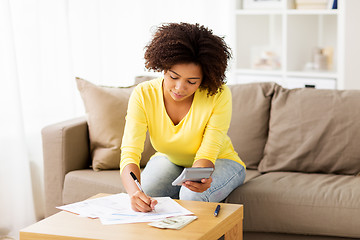 Image showing african woman with papers and calculator at home