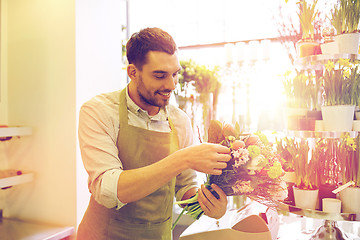 Image showing smiling florist man making bunch at flower shop