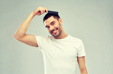 Image showing happy man brushing hair with comb over gray