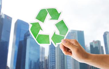 Image showing close up of hand with green recycle sign in city