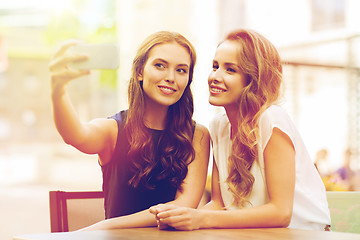 Image showing happy women with smartphone taking selfie at cafe