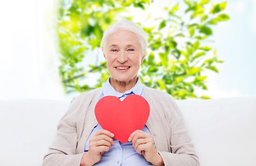 Image showing happy smiling senior woman with red heart at home