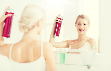 Image showing woman with hairspray styling her hair at bathroom