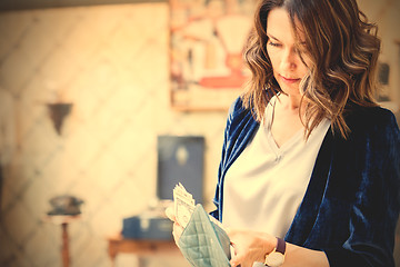 Image showing woman in a blue jacket counts the money