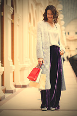 Image showing woman in a fashionable knitted coat with shopping bags